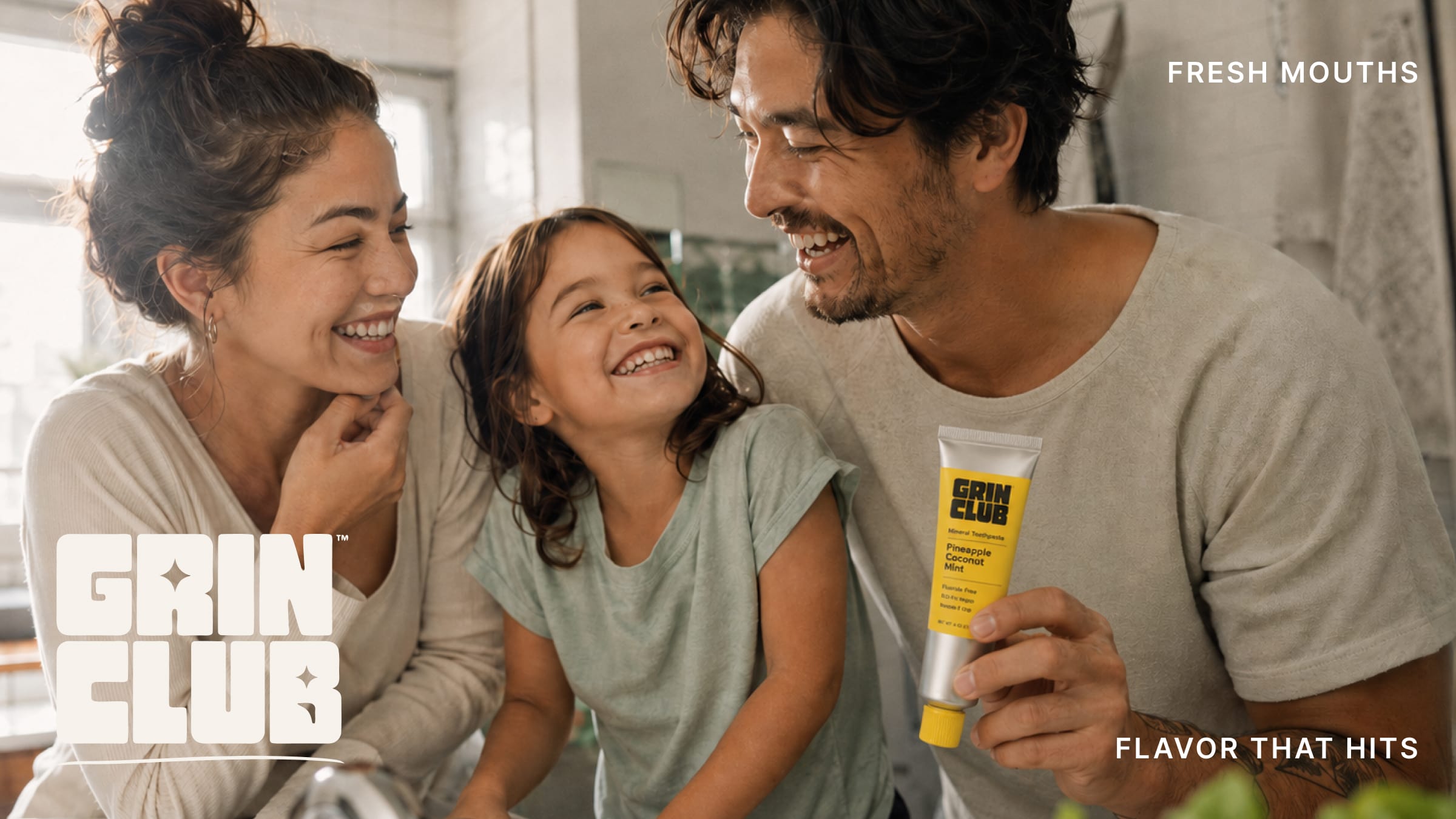 A family laughing together as the father holds a yellow Grin Club tube.