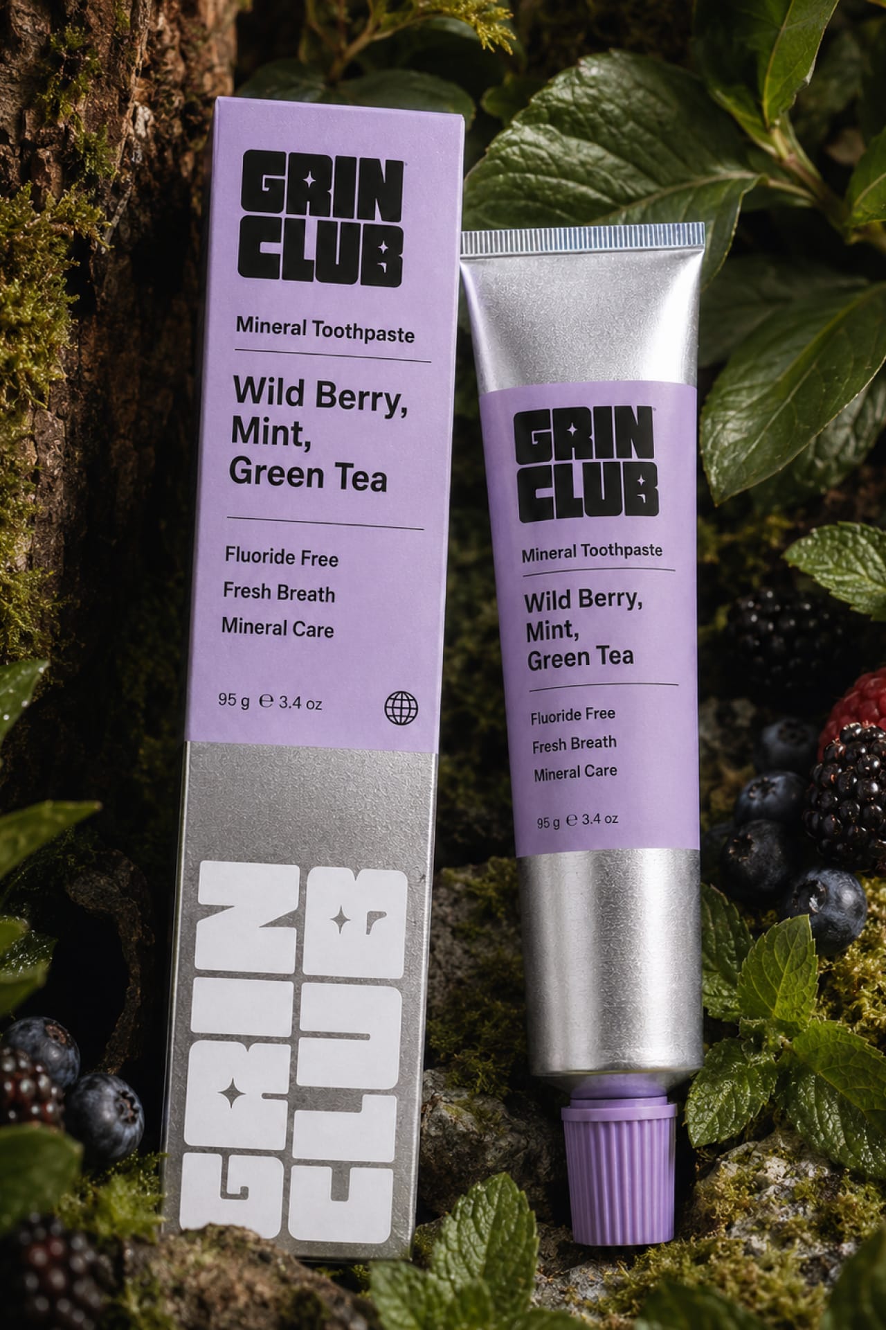 The lilac Wild Berry Grin Club box and tube among moss and berries.