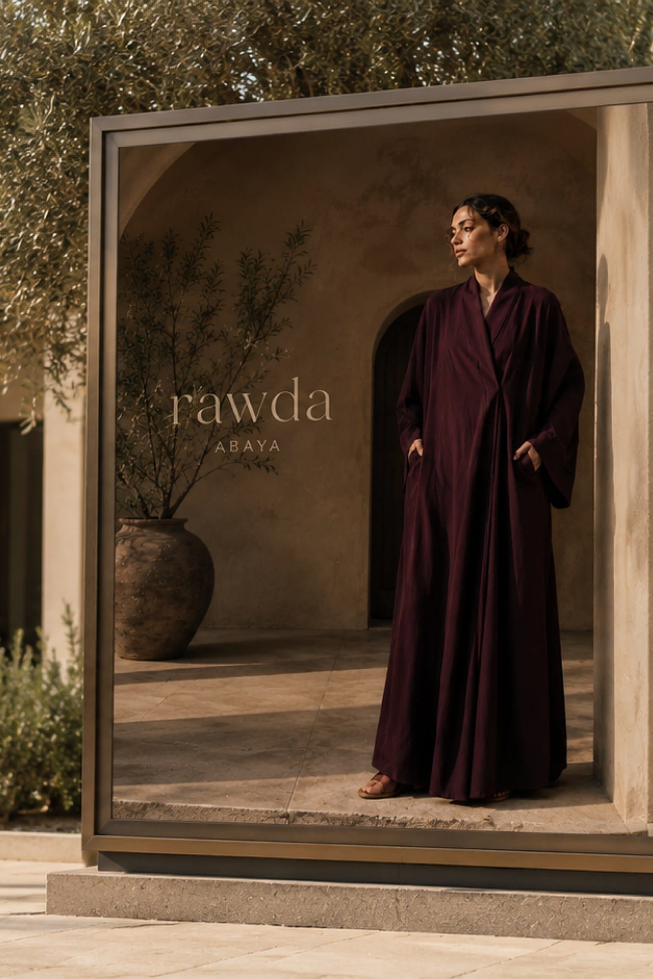 An outdoor display panel, a model in an oxblood abaya.