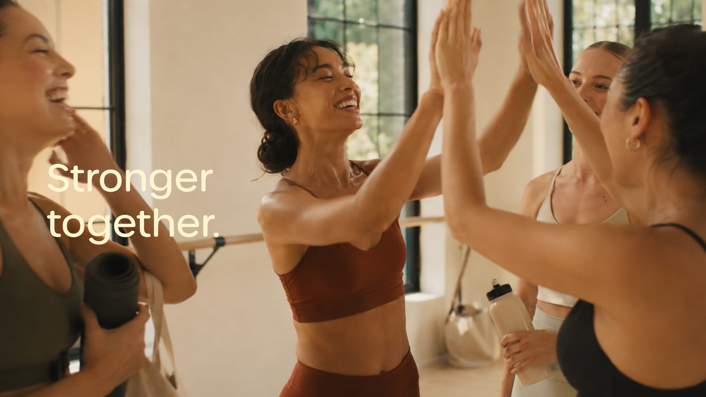 Women high-fiving in a bright class beside Stronger together.