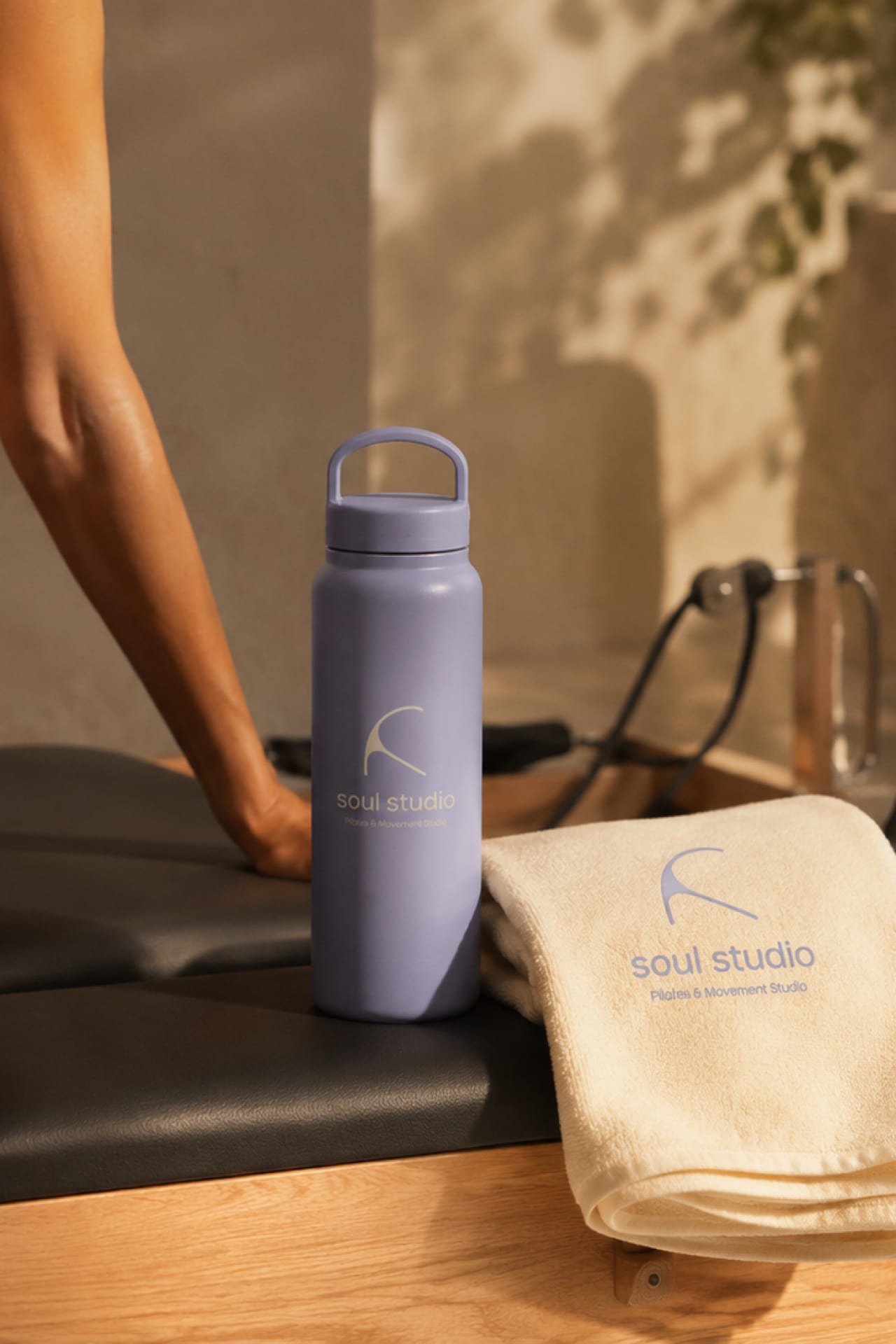 A branded water bottle and towel on a studio bench.