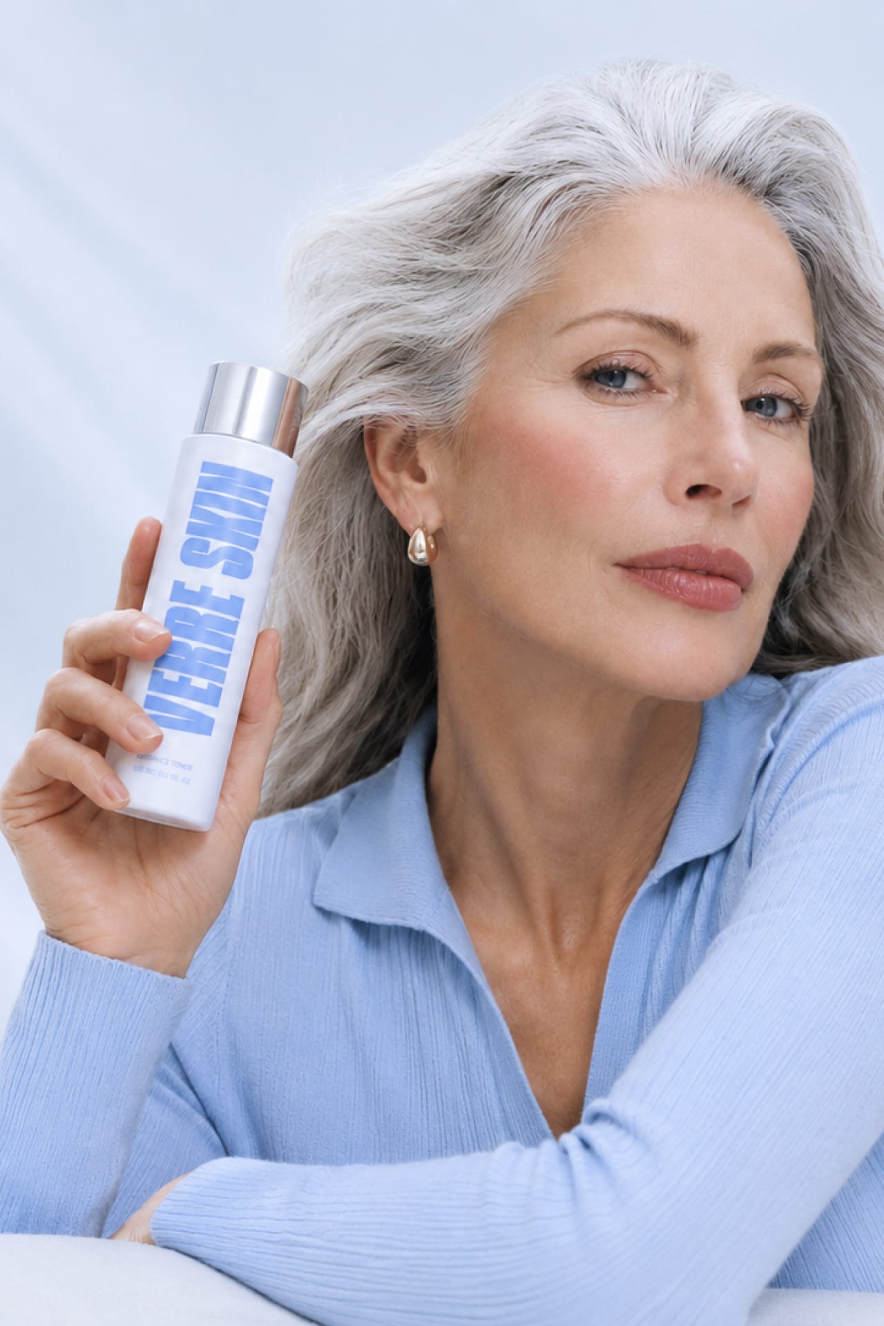 A silver-haired woman holding the Verre Skin essence toner.
